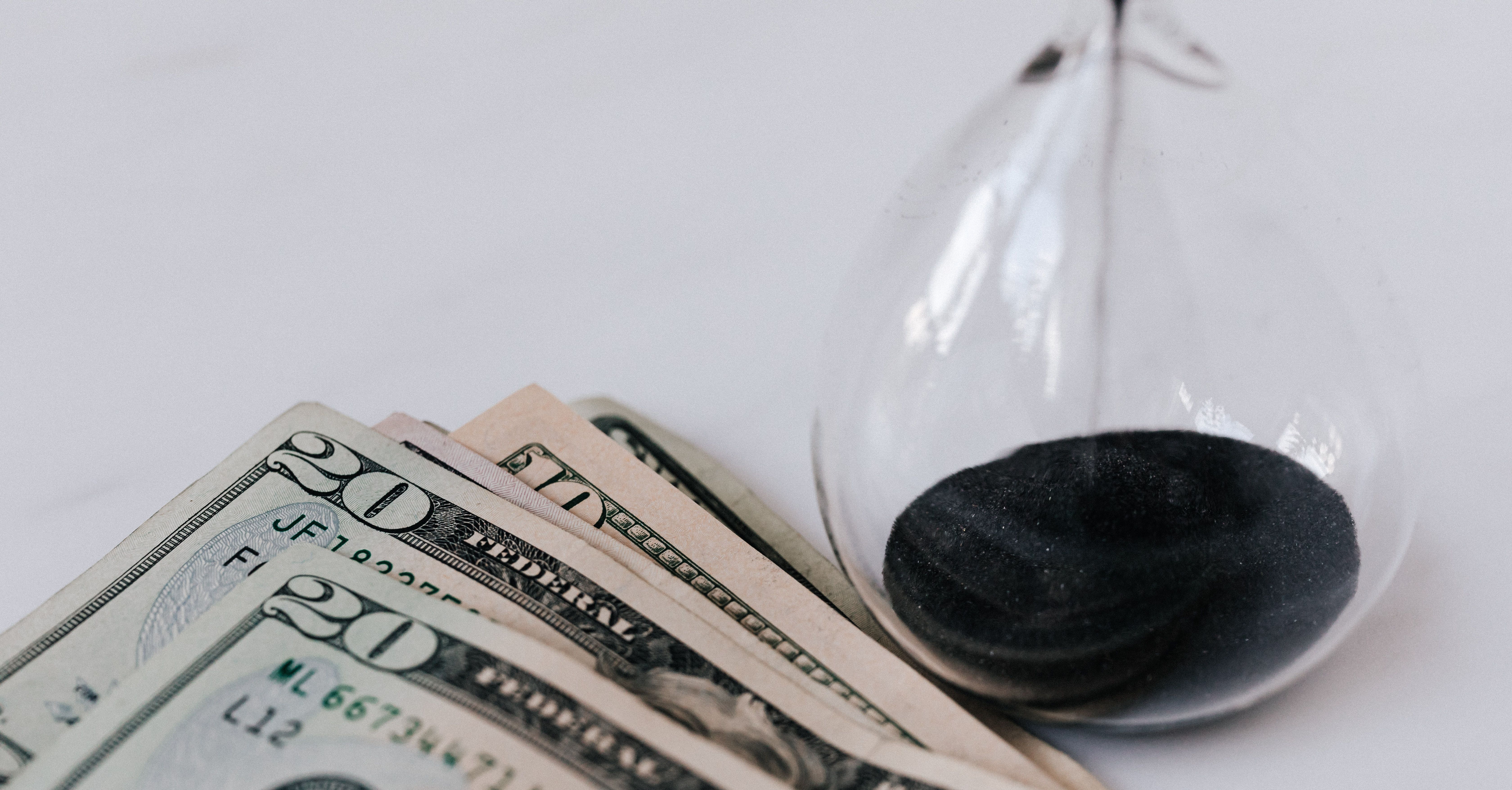 sand timer next to twenty dollar bills