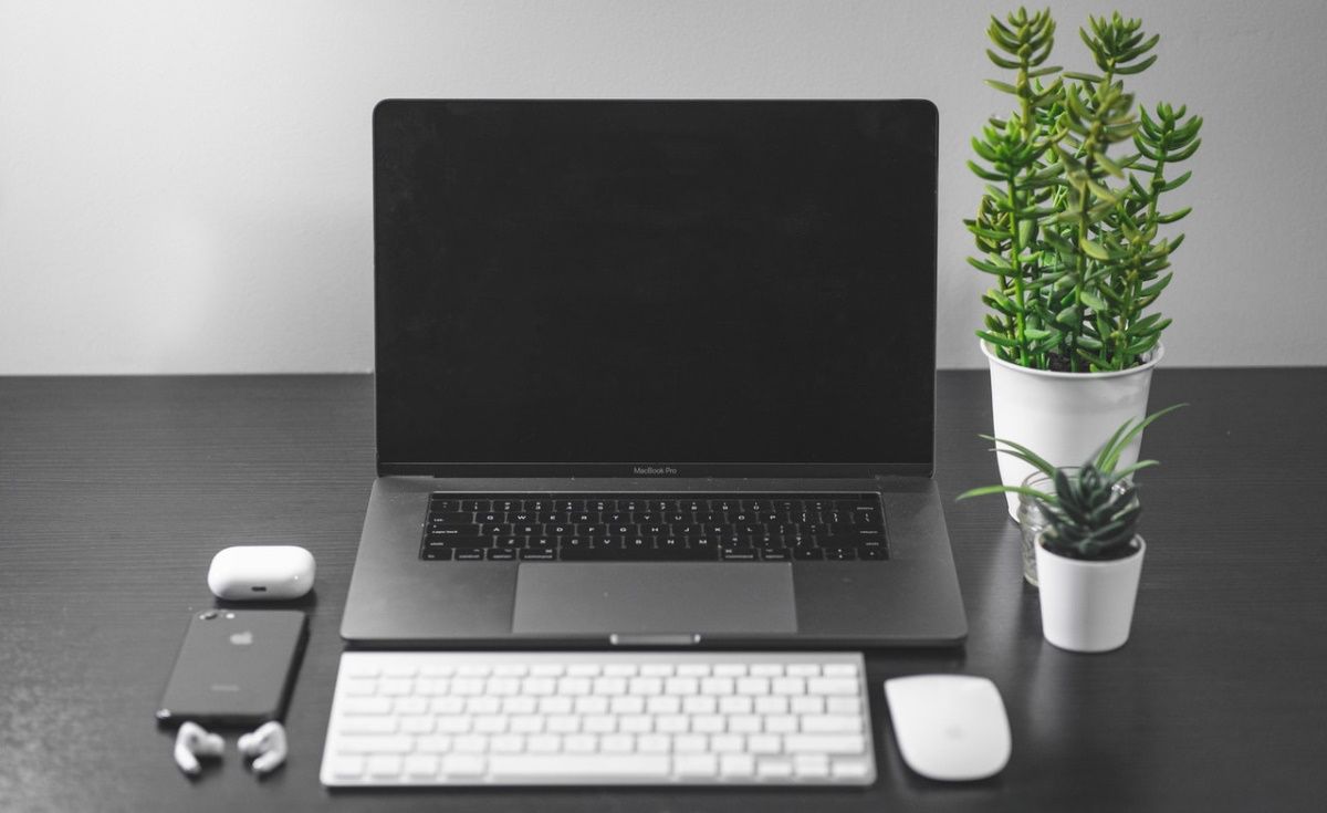 A MacBook, Magic Keyboard, Magic Mouse, iPhone, and AirPods.